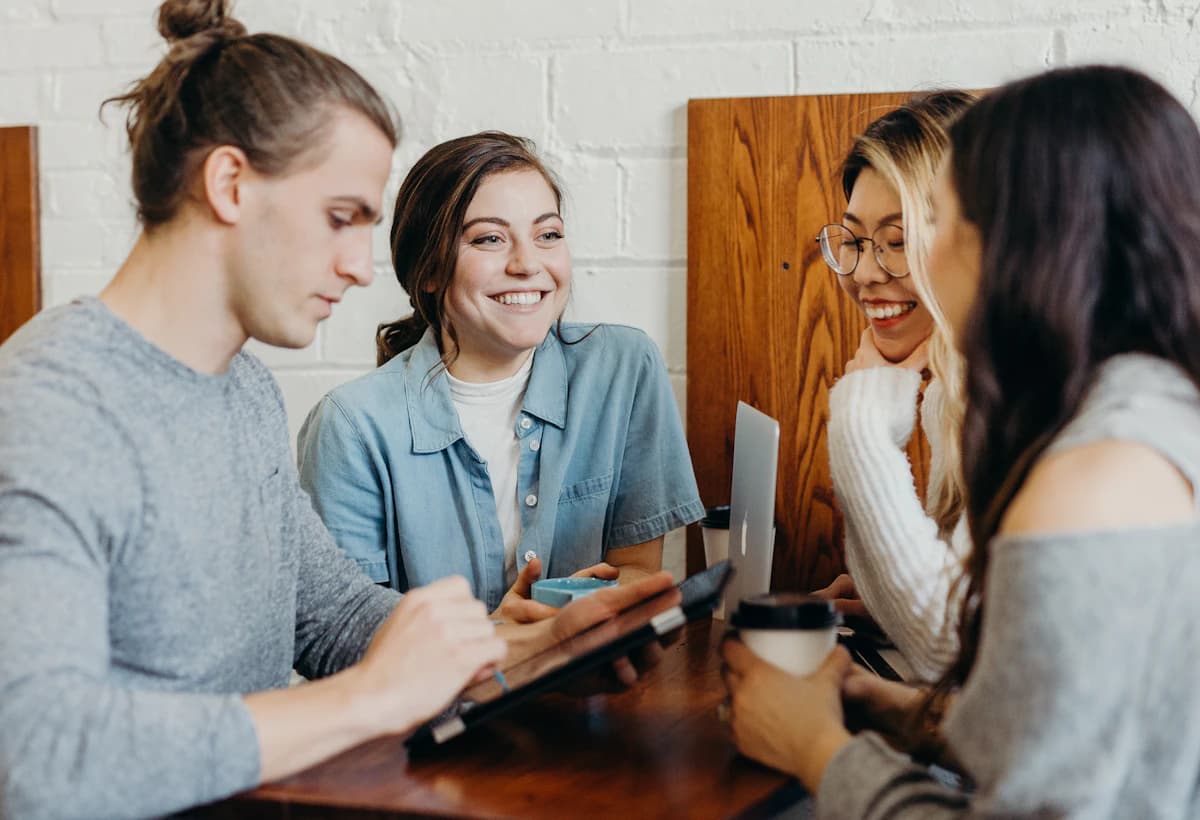 A team of colleagues smiling around a laptop in a bright office